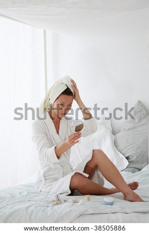 young woman sitting on bed and makes make up