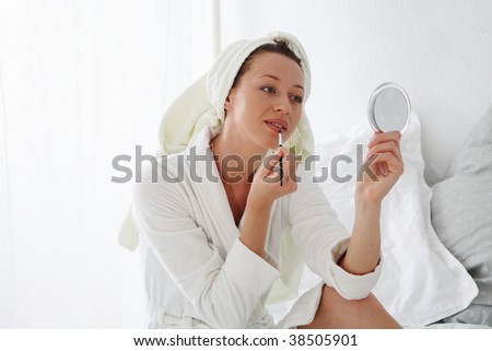 young woman sitting on bed and makes make up
