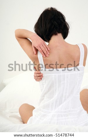young woman sitting in bed with backache
