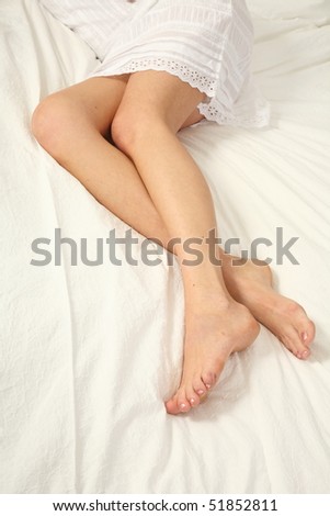 young woman lies on her bed with long legs
