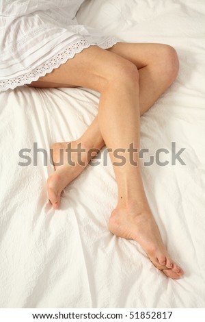young woman lies on her bed with long legs