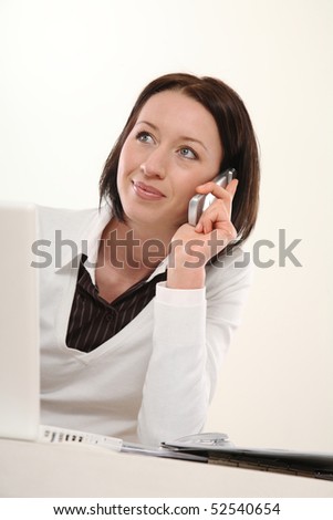 young woman sitting at the table in office and telephones