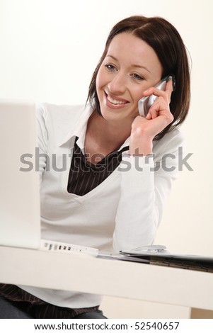 young woman sitting at the table in office and telephones