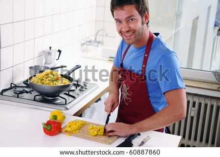 young man stand in the kitchen and cut vegetable