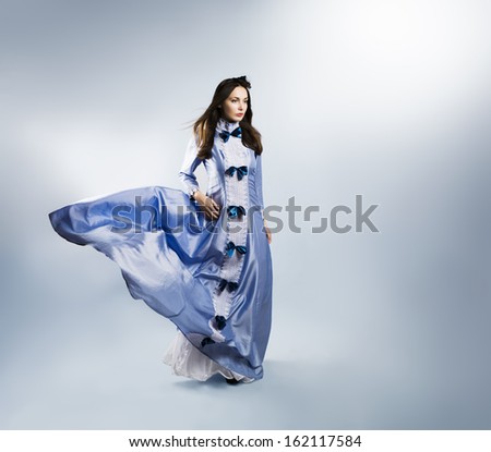 Full Length Portrait of a Woman in Waving Purple Dress on Gray Backgound