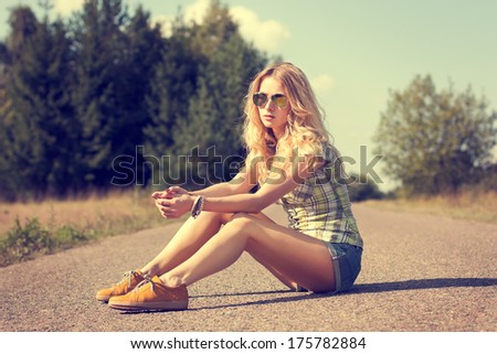 Trendy Hipster Girl Sitting On The Road. Toned Photo. Modern Youth Lifestyle Concept.