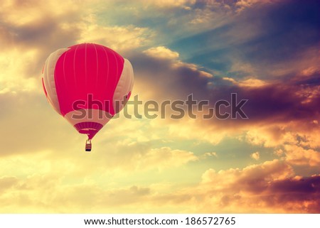 Red Hot Air Balloon Flying over Dramatic Sunset Sky. Toned Photo. Travel Concept.