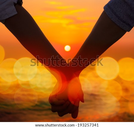 Closeup of a Hands of a Couple Held Together on the Background of Sea Sunset. Toned Instagram Styled Photo with Bokeh. Romantic Summer Travel Concept.