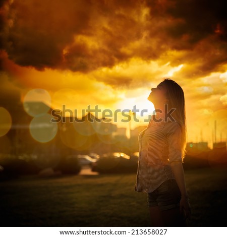 Silhouette of Young Woman at Urban Sunset. Dramatic Sky. Toned Instagram Styled Photo.