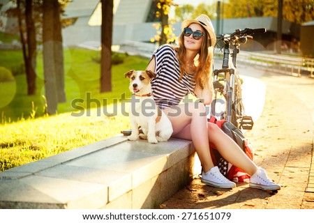 Smiling Hipster Girl with her Dog and Bike in the City. Toned and Filtered Photo with Bokeh and Copy Space. Urban Youth Lifestyle Concept.