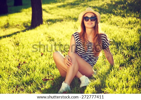 Happy Hipster Girl Relaxing on the Grass. Toned and Filtered Photo. Modern Youth Lifestyle Concept.