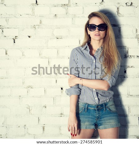 Portrait of Young Hipster Woman on White Brick Wall Background. Trendy Casual Fashion Concept. Street Style Outfit. Toned Instagram Styled Photo.