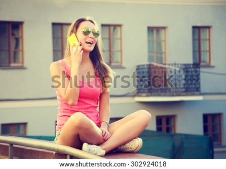 Happy Girl Talking by the Phone Outdoors. Modern Teenager Lifestyle Concept. Toned Photo with Copy Space.