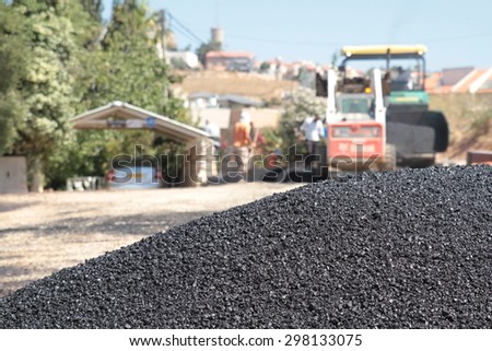 Worker operating asphalt paver machine during road construction and repairing works