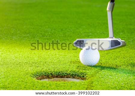 golf ball from the hole with the putter on golf turf
