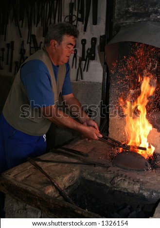 Working smith by traditional way in  his father's forge in a little village