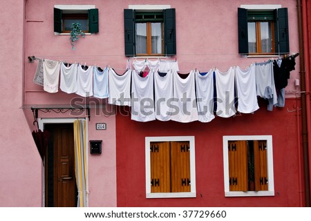 Drying clothes on a pink and red house in Burano, Italy