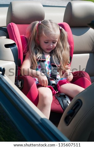 Little cute girl sitting in car seat