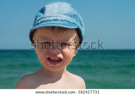 Cute little boy in denim cap on the beach