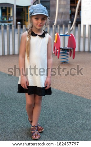 Young girl in white dress and denim cap on the playground