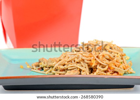 Meat and noodles in blue plate. Red take away box on the background.