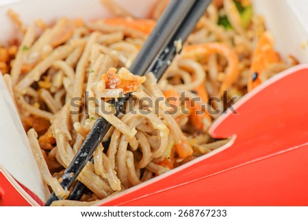 Closeup of meat and noodles in red take away container. Shallow depth of field.