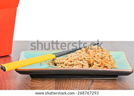 Meat and noodles in blue plate with chopsticks on wooden table. Red take away box.