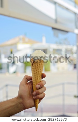 Men\'s hand holding white ice cream waffle cone