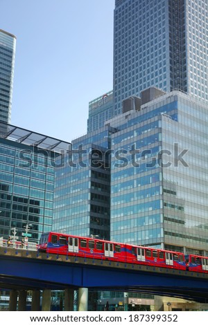 LONDON, CANARY WHARF UK - APRIL 13, 2014: - DLR bridge with train. Modern glass architecture of Canary Wharf business aria, headquarters for banks, insurance, media and other world known companies.