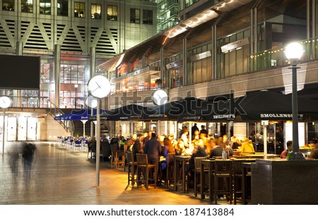 LONDON, CANARY WHARF UK - APRIL 4, 2014:  Canary Wharf square view in night lights with office workers chilling out after working day in local cafes and pubs