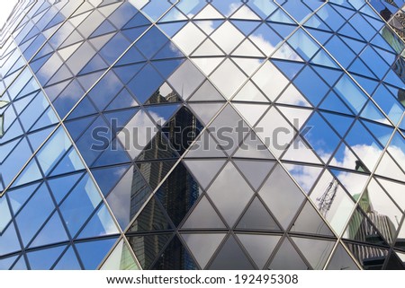 LONDON, UK - APRIL 24, 2014: Ghirkin building glass windows texture reflects the sky. The modern glass buildings of the Swiss Re Gherkin, is 180 meters tall, stands in the City of London