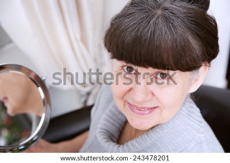 Pension age good looking woman looking in mirror