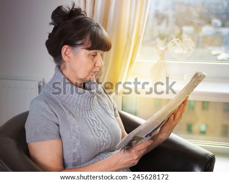 Pension age good looking woman portrait reading the news