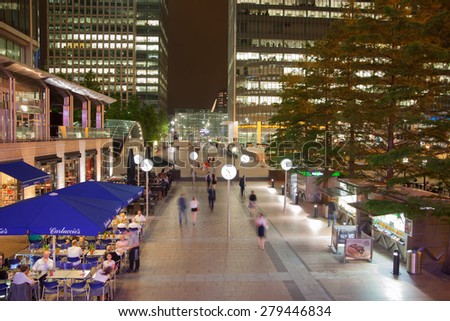LONDON, UK - JULY 29, 2014: Canary Wharf square view in night lights with office workers chilling out after working day in local cafes and pubs and walking through the square
