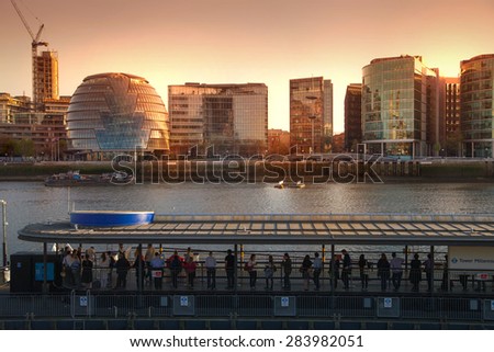 LONDON, UK - APRIL 15, 2015: Modern buildings on the south bank of river Thames walk in sunset. Office centre, theatre and London city hall building