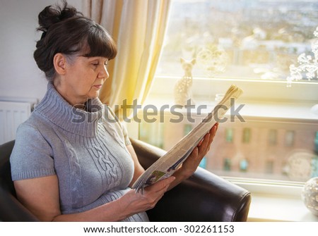 Pension age good looking woman reading news paper