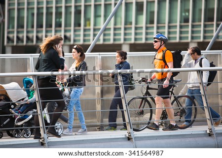 LONDON, UK - SEPTEMBER 9, 2015: Lots of people crossing bridge on the way to work. Canary Wharf business life