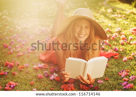 Beautiful Young Woman Reading a Book Outside on the Grass
