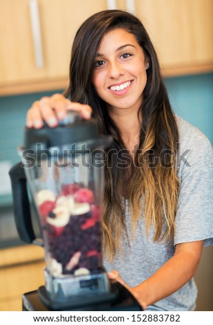 Beautiful Young Woman Making Fruit Smoothie in Blender