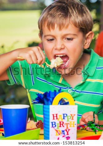 Happy Young Boy Eating Cake at Birthday Party