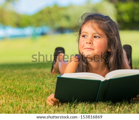 Cute Little Girl Reading Book Outside on Grass