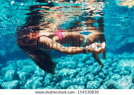 Attractive young woman floating in beautiful ethereal natural ocean pool, Underwater View