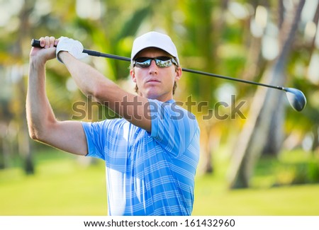 Athletic young man playing golf, Golfer hitting fairway shot, swinging club