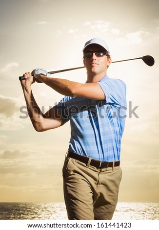 Golfer at sunset, Man swinging golf club with dramatic sunset sky