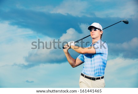 Golfer at sunset, Man swinging golf club with dramatic blue sky
