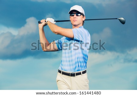 Golfer at sunset, Man swinging golf club with dramatic blue sky