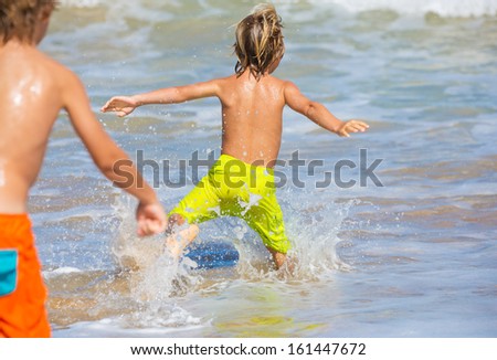 Two young boys having fun on tropical beach, happy best friends playing