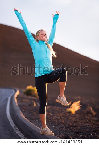 Young attractive athletic woman, wearing sporty cloths on trail, stretching before run