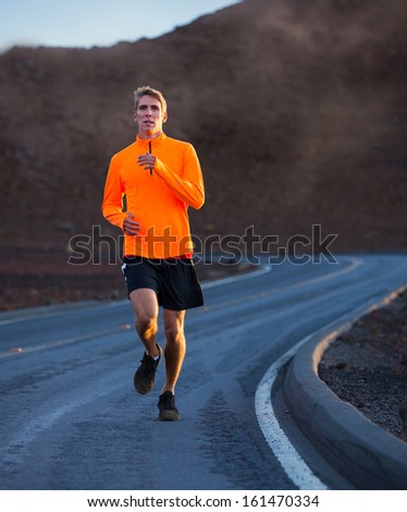 Athletic man jogging outside, training outdoors. Running on road at sunset
