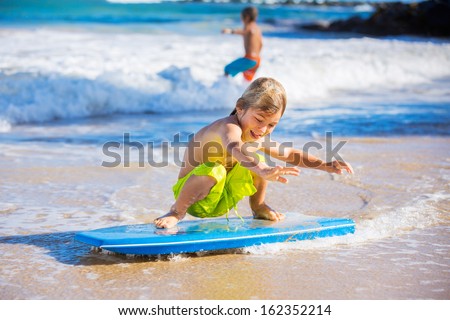 Happy Young boy having fun at the beach on vacation, with boogie board